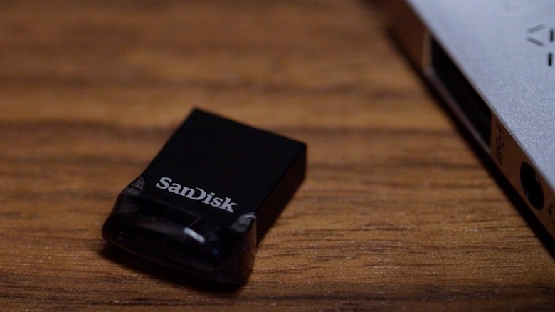 Close-up of a Sandisk Ultra Fit USB 3.2 Gen 1 Flash Drive placed on wooden table next to laptop