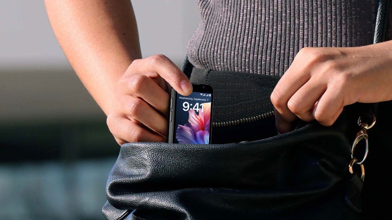 An individual placing a BLKE AIR HD Touch Screen Mini Smartphone into their black purse, the image is a closeup of the purse