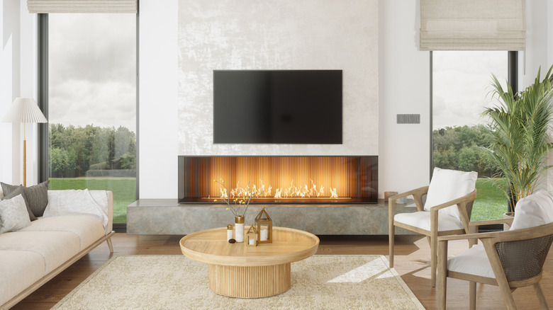 A TV mounted above a fireplace in a modern beige-toned living room