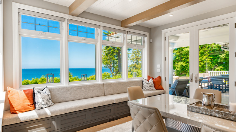 A nicely designed living area that contains several large windows that give a view of several trees and a body of water