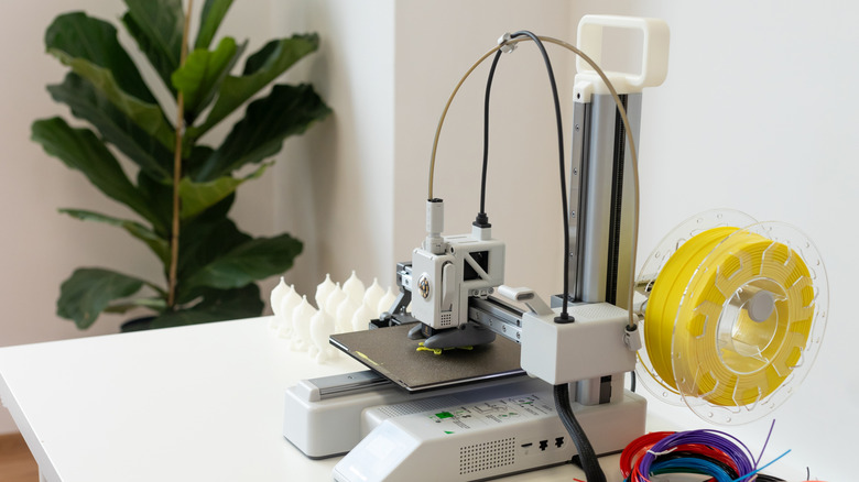 Working 3D printer with filament placed on a white table