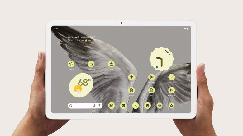 Google Pixel Tablet held in hands displaying home screen interface