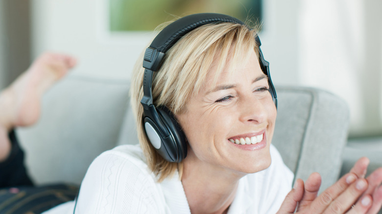 Woman with over-ear headphones lying on a couch