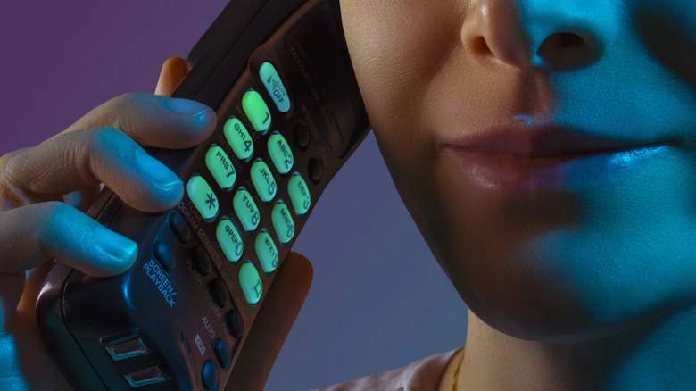 Woman holding old cordless phone to her ear.