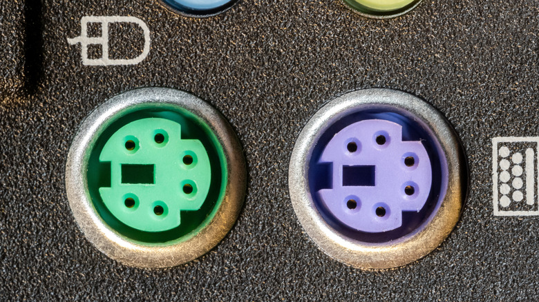 Two circular color-coded sockets with symbols for a mouse beside the left one and a keyboard beside the right one