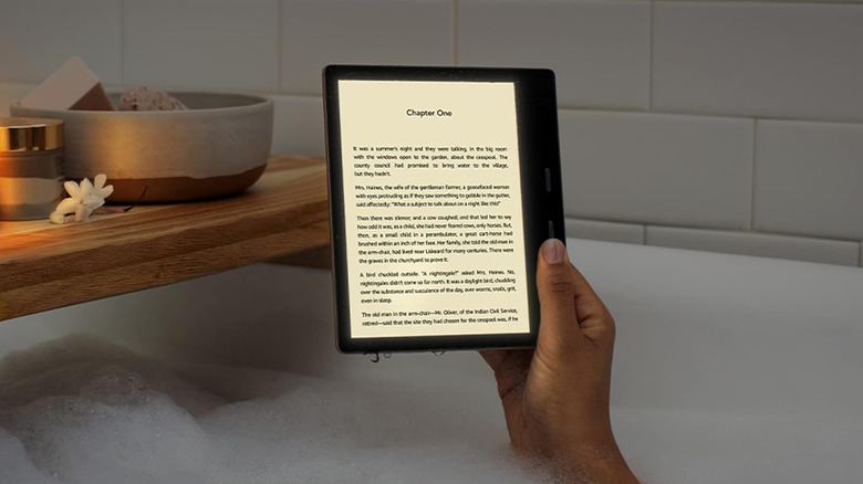 Kindle Oasis 3 held above a bathtub with a book page open on the screen.