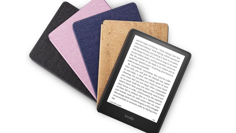 Kindle Paperwhite 5 displayed beside black, pink, blue, and cork-style fabric covers.