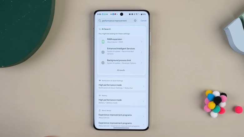 OnePlus phone on table showing OxygenOS AI Search in Settings