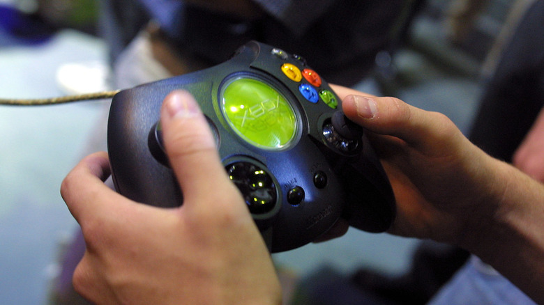Person holding an original Xbox controller