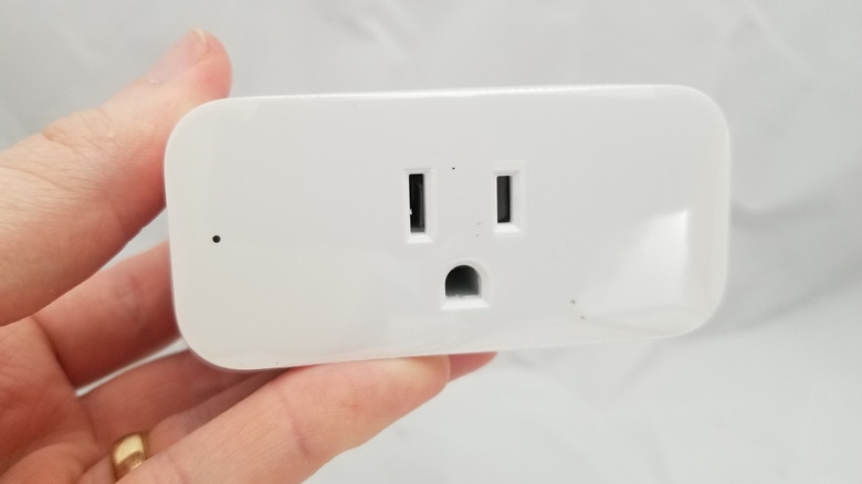 A person holding an outdated Amazon Echo smart plug