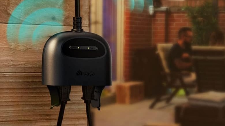 The Kasa EP40A Outdoor Smart Plug connected near a person sitting on a backyard patio.