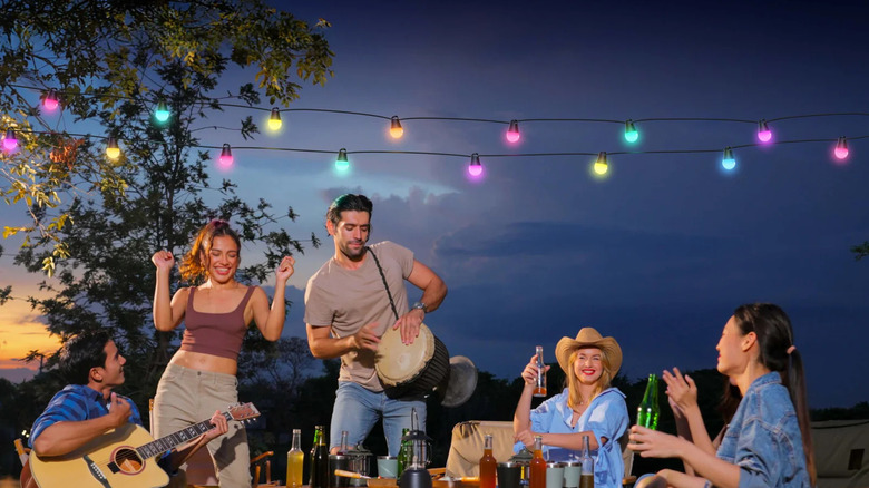 The Govee Smart Outdoor String Lights 2 set up over a bunch of people playing musical instruments outside.