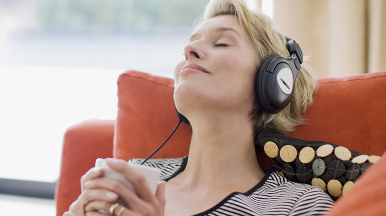 Person relaxing on a couch while wearing over-ear headphones.