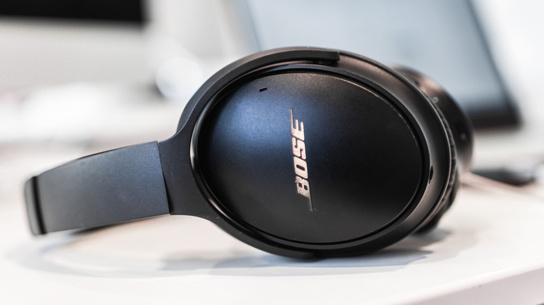 A pair of black Bose headphones on their side on a desk.