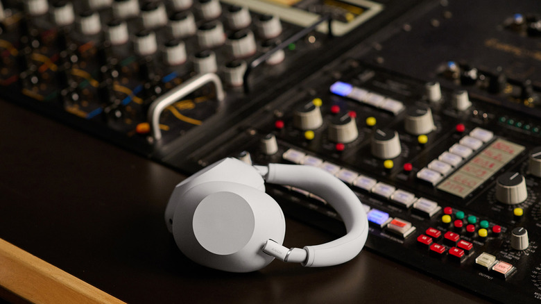 A pair of white Sony WH100MX6 headphones atop an audio switchboard.