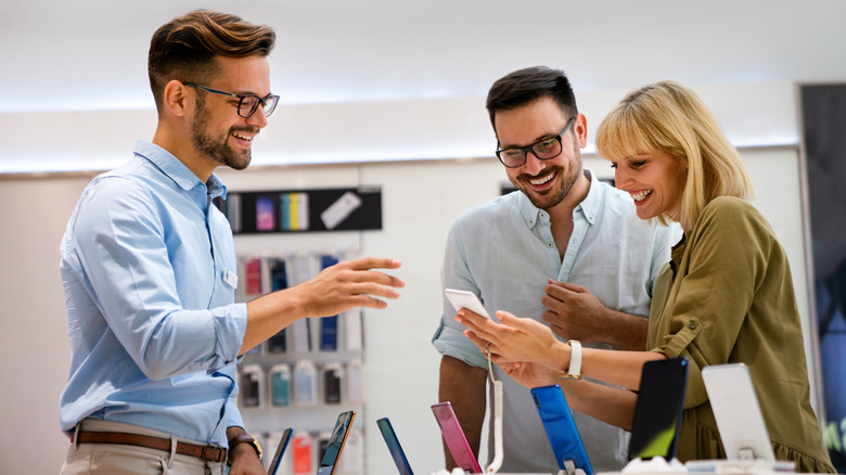 A salesperson helping a couple choose a phone.