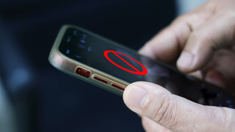 A person holding a phone with a restricted sign on the screen.