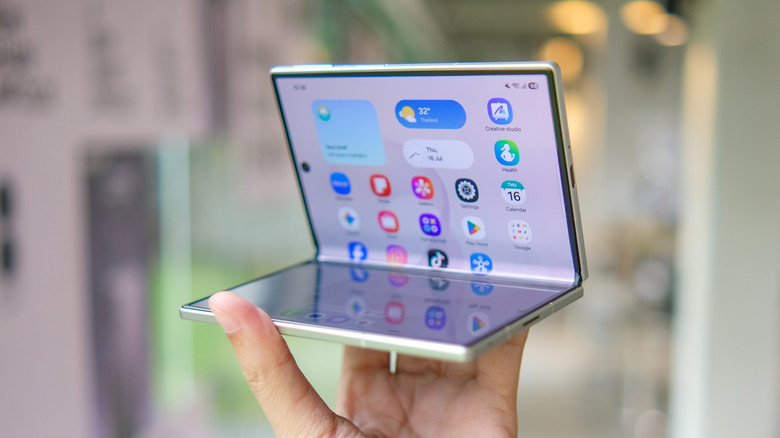 Samsung foldable phone held open with the inner display and app icons visible.