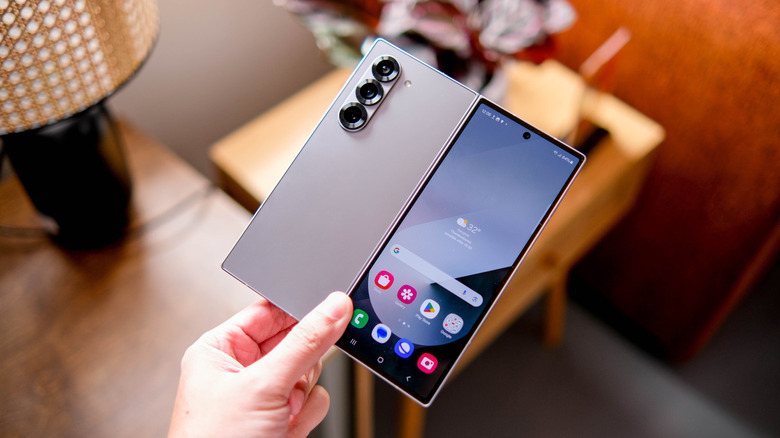 Samsung foldable phone held partially open with its rear cameras and inner screen visible.