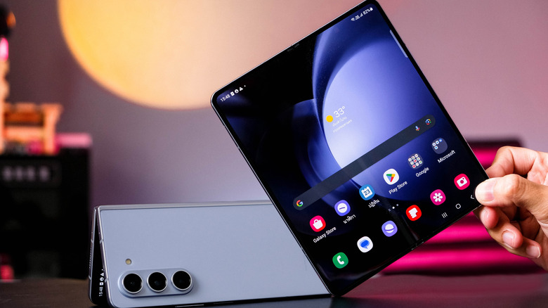 Samsung foldable phone shown open beside another device with rear cameras visible.
