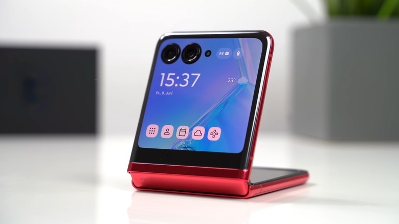 A red Motorola Razr folding smartphone sits on a white surface
