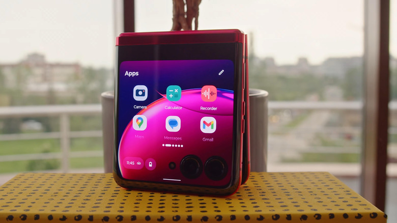 A red Motorola Razr displays two rows of app icons on its cover screen, apps include Gmail, Camera, and Calculator