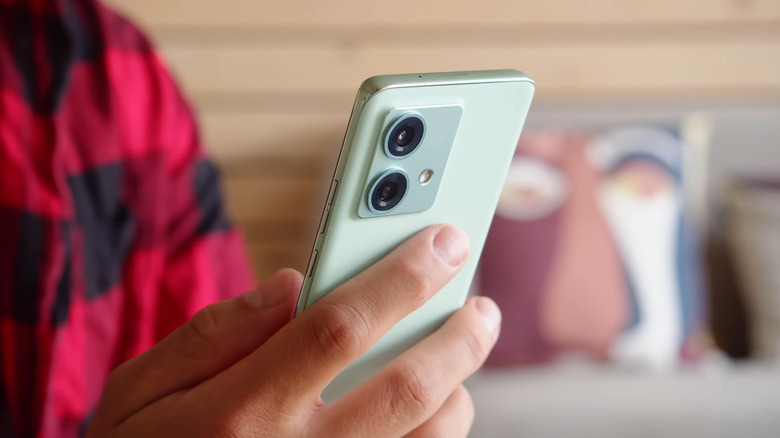 Person holding a green Motorola Edge phone with the rear cameras visible.