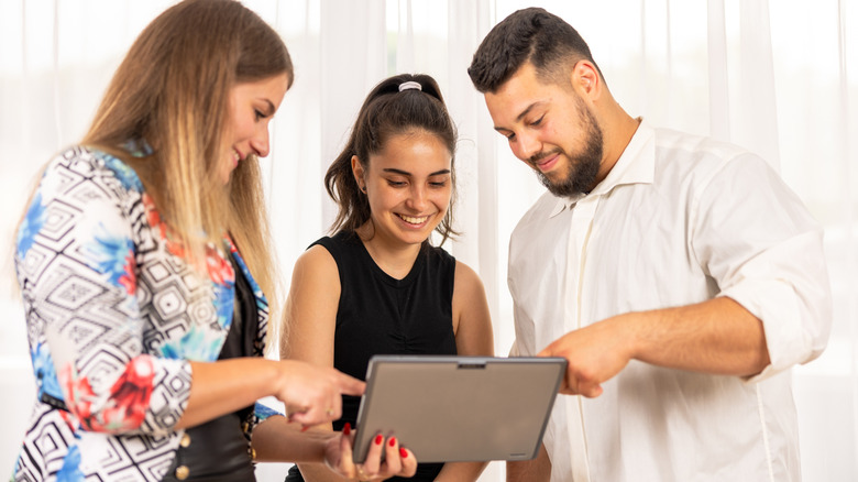 Several people looking at a tablet screen