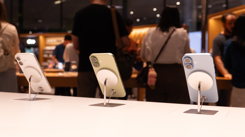 three iPhone 17 on display inside an Apple Store with customers standing in the background