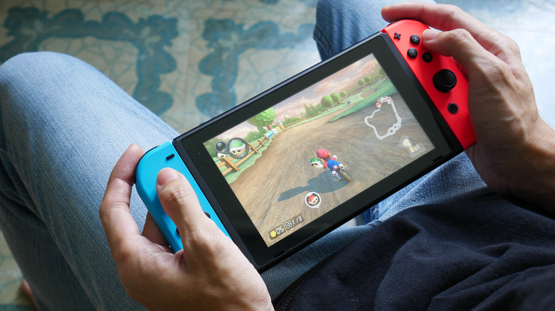 Person playing Mario Kart 8 Deluxe on Nintendo Switch in handheld mode