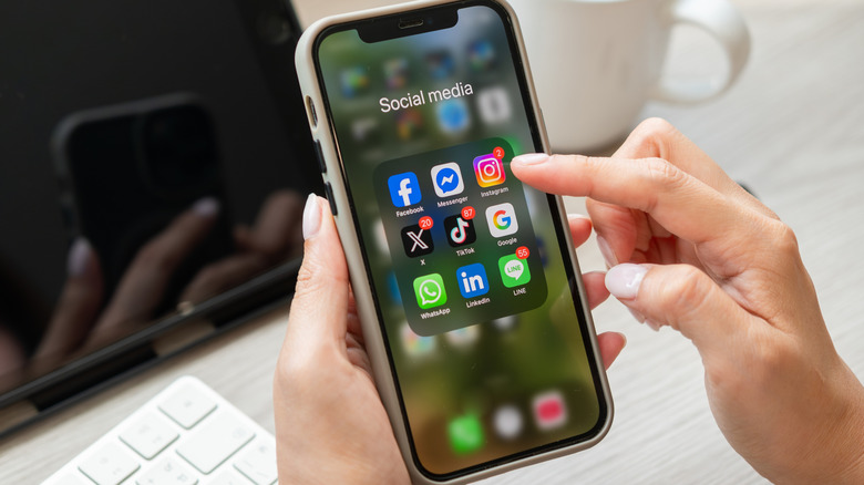 A person using their phone, looking at various social media apps