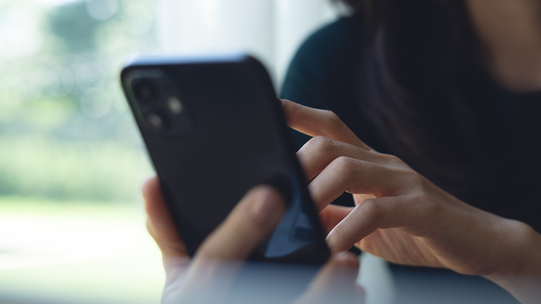 A woman tapping on her phone screen