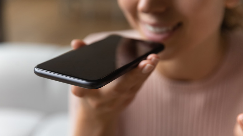 A person speaking into the bottom of a smartphone.