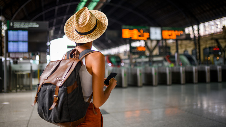A traveler with a backpack waiting at a train station.