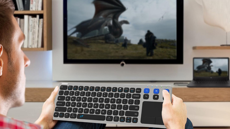 A man using the Arteck HD197 keyboard with a smart TV