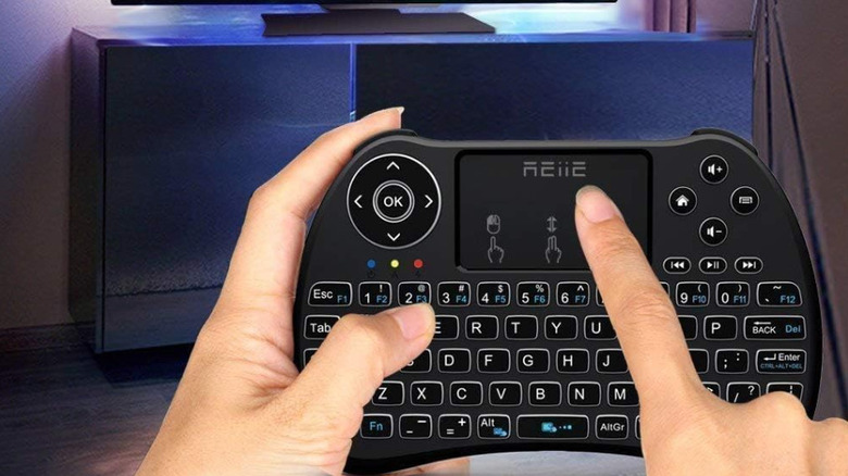 A person using the Reiie H9+ Mini keyboard in front of an entertainment center
