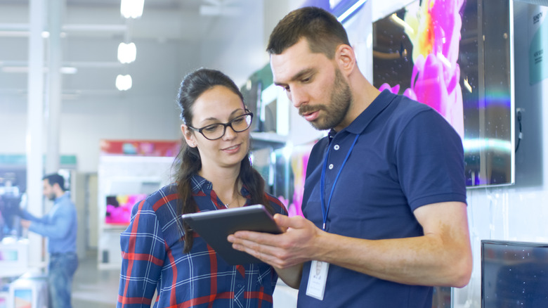 People discussing a tablet sale in an electronics store