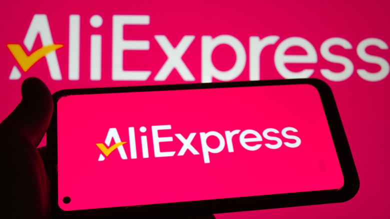 A phone with the AliExpress logo on it in front of a screen with a larger AliExpress logo