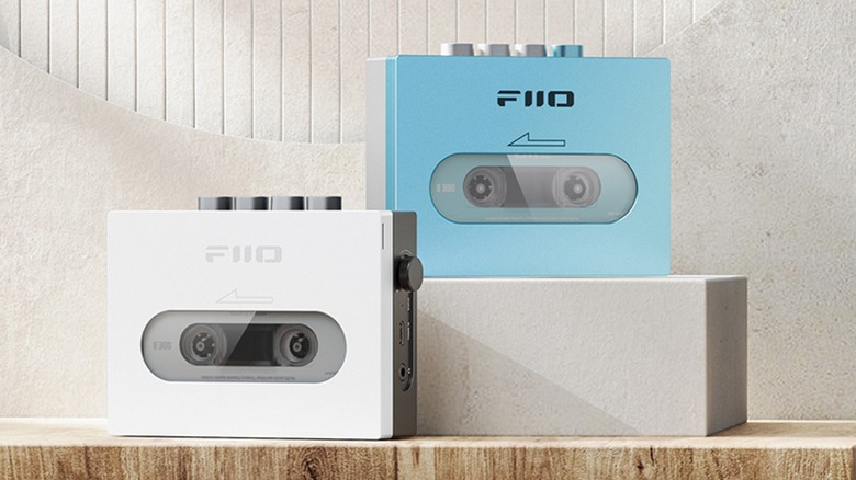 Two FiiO CP13 Cassette Players -- one light blue, one white -- sit against a concrete-like backdrop, the blue model sits a little higher than the white one