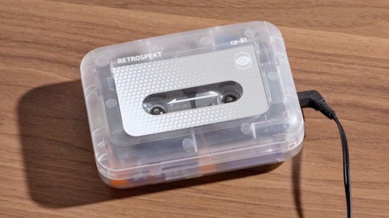A translucent Retrospekt CP-81 Portable Cassette Player sits on top of a wooden surface