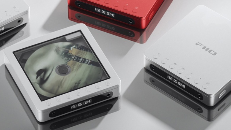 Three FiiO DM13 CD players sit on a flat, white surface, one of the players has a clear window for viewing a spinning CD whereas the other one doesn't