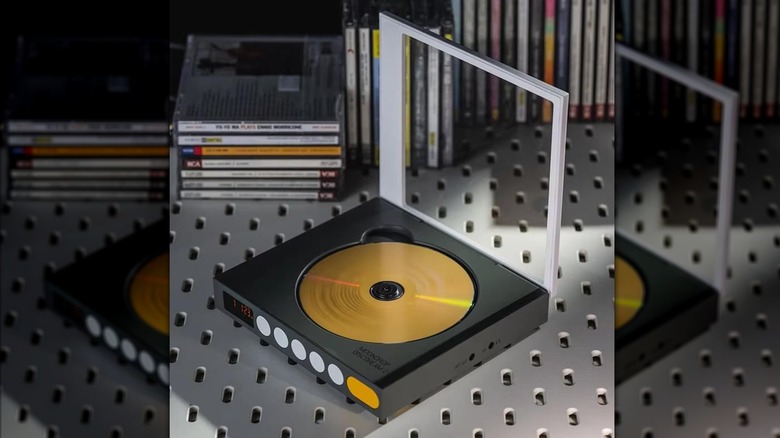 A black and silver Moondrop Discdream 2 CD player sits on a metal surface next to several stacks of CDs