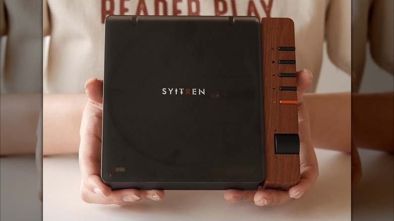 A black Synitren R300 Retro with wood trim, the device is being held between an individual's hands