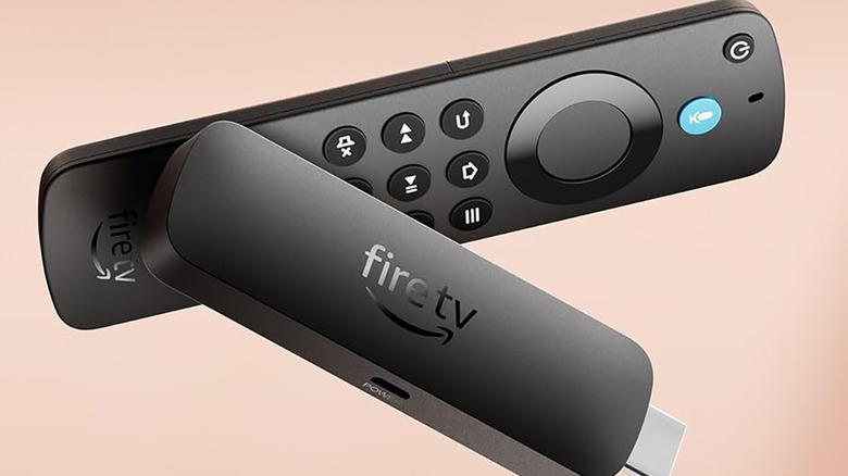 An Amazon Fire TV Stick 4K Select on its side with remote, on a light pink background.