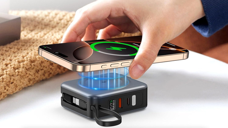 A hand placing a phone down on a magnetic enabled portable charger.