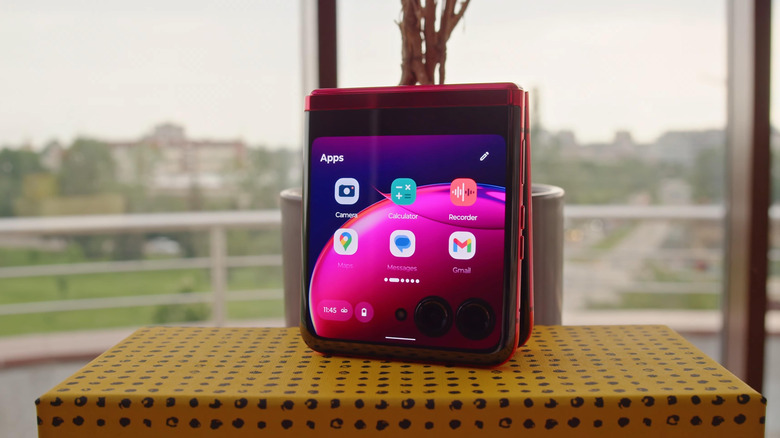 Red foldable Motorola Razr phone closed with apps shown on its external display.