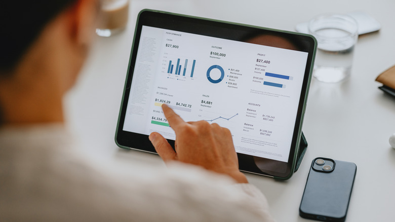 Person using a tablet to view business analytics beside a smartphone.
