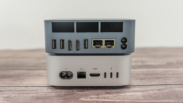 Two mini PCs stacked on top of each other on a wooden surface.