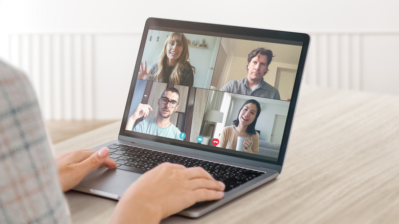 A person taking a video call with three other people on a laptop.