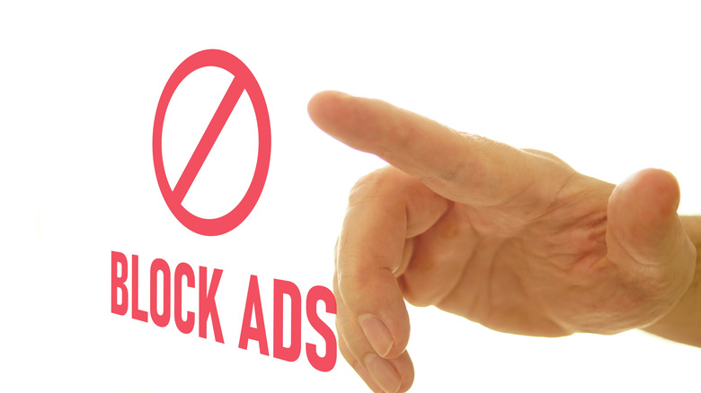 Hand pointing at a "block ads" sign